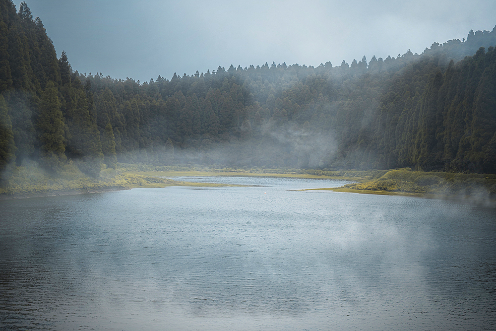 Lagoa do Eguas lake framed by a forest in a cloudy day with some low fog, Azores islands, Sao Miguel island, Portugal, Atlantic, Europe