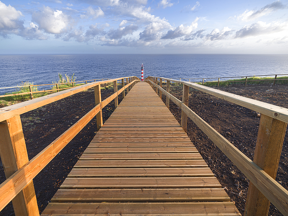 Farolim dos Fenais da Ajuda lighthouse with a symmetrical wooden path leading to it, Sao Miguel island, Azores Islands, Portugal, Atlantic, Europe