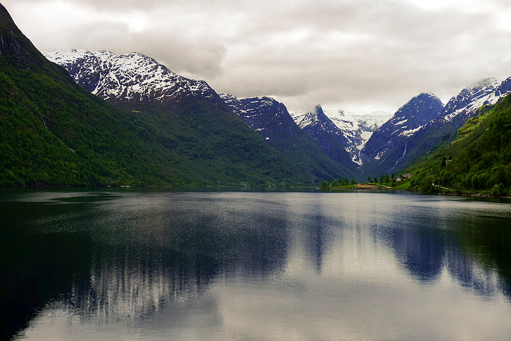 Snow-capped mountains reflected in the still waters of a Norwegian fjord, Stryn, Vestland, Norway, Scandinavia, Europe