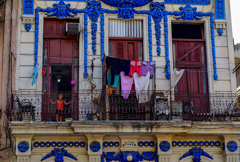 Small child in doorway on a balcony with drying clothes, Havana, Cuba, West Indies, Central America