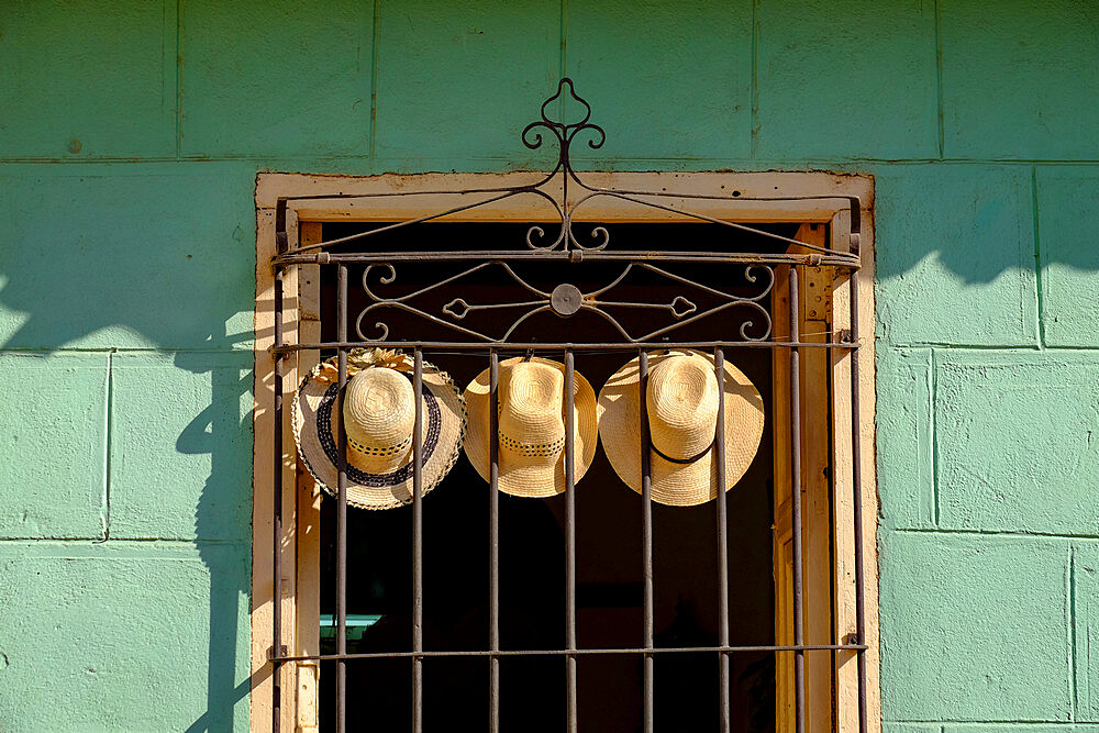 Three straw hats hang on an iron grate in a window, Trinidad, Cuba, West Indies, Central America