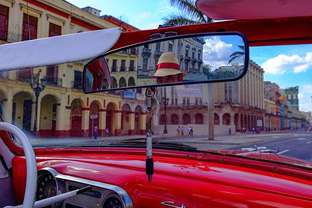 Taxi driver in straw hat seen in rear-view mirror of vintage car, Havana, Cuba, West Indies, Central America