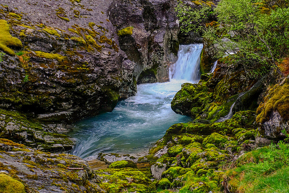 Water forms waterfalls and ponds as it snakes its way down a mountain at Briksdal glacier, Stryn, Vestland, Norway, Scandinavia, Europe