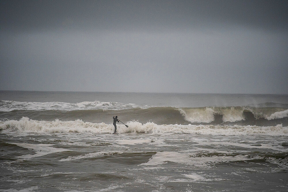 Man trying to get out through big shorebreak on his stand up paddle board, Nags Head, North Carolina, United States of America, North America