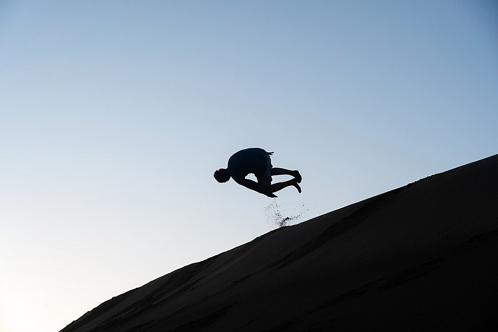 Silhouette of a man tumbling down a sand dune in Nags Head, North Carolina, United States of America, North America