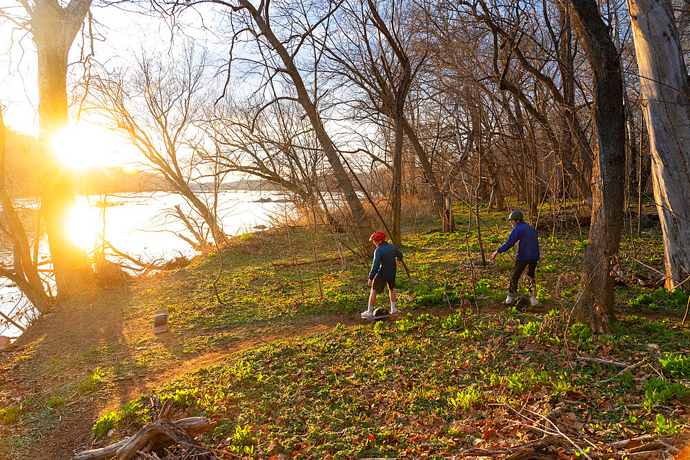 Brothers ride their One-Wheels on a single track mountain biking trail next to the Potomac River. Bethesda, Maryland, United States of America, North America