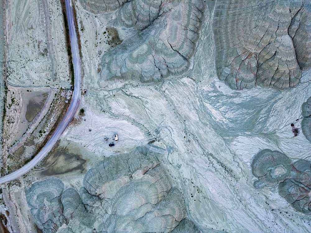 Drone aerial view of camper vans with solar panels on a dry grey mountain landscape