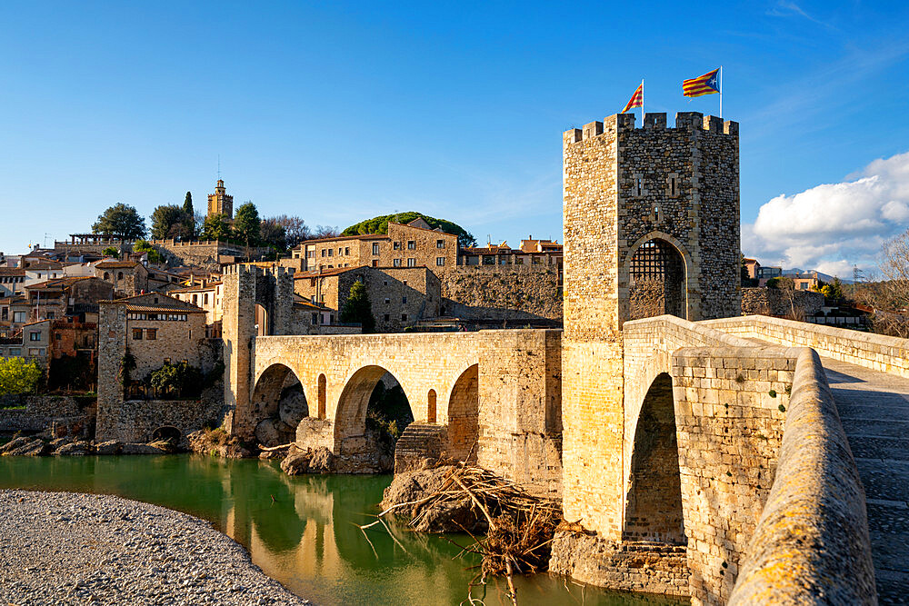 Besalu historic medieval city with Catalonia flags on the stone bridge tower crossing El Fluvia river, Besalu, Catalonia, Spain, Europe