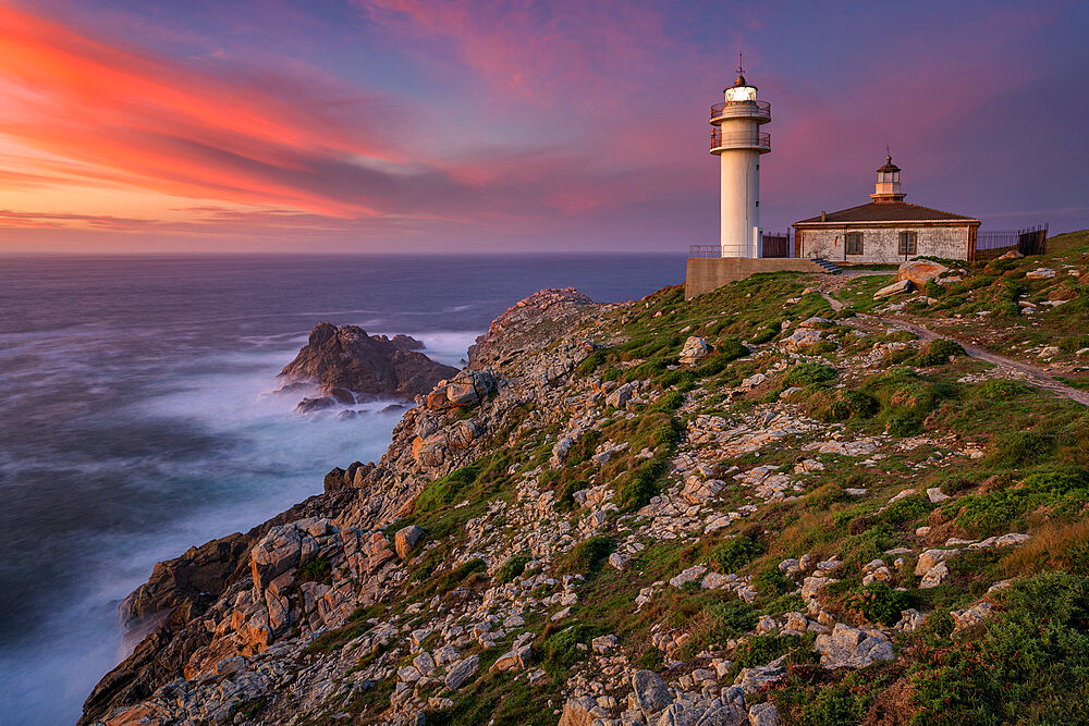 Sea landscape view of Cape Tourinan Lighthouse at sunset with pink clouds, Galicia, Spain, Europe