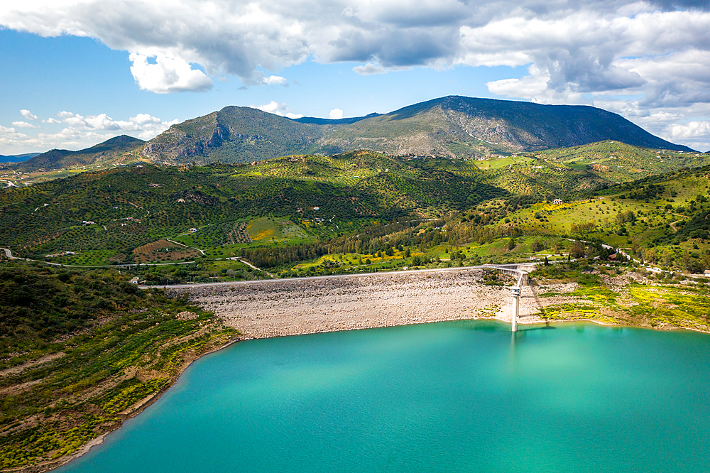 Drone aerial view of Zahara de la Sierra water reservoir dam with turquoise water and mountains in the background, Andalusia, Spain, Europe