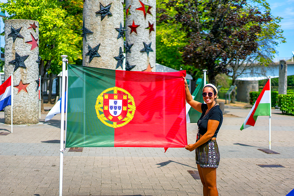 Young woman holding the Portuguese flag in Schengen European center, Schengen, Luxembourg, Europe