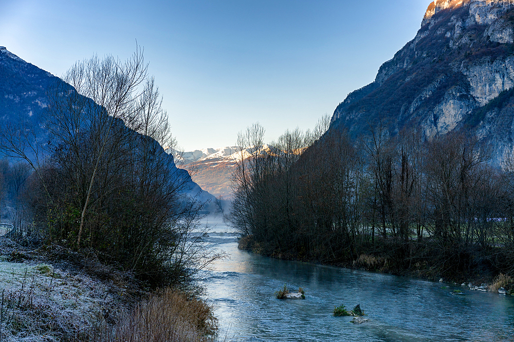 Landscape view of a river and mountain in the background covered in snow during winter, Italy, Europe