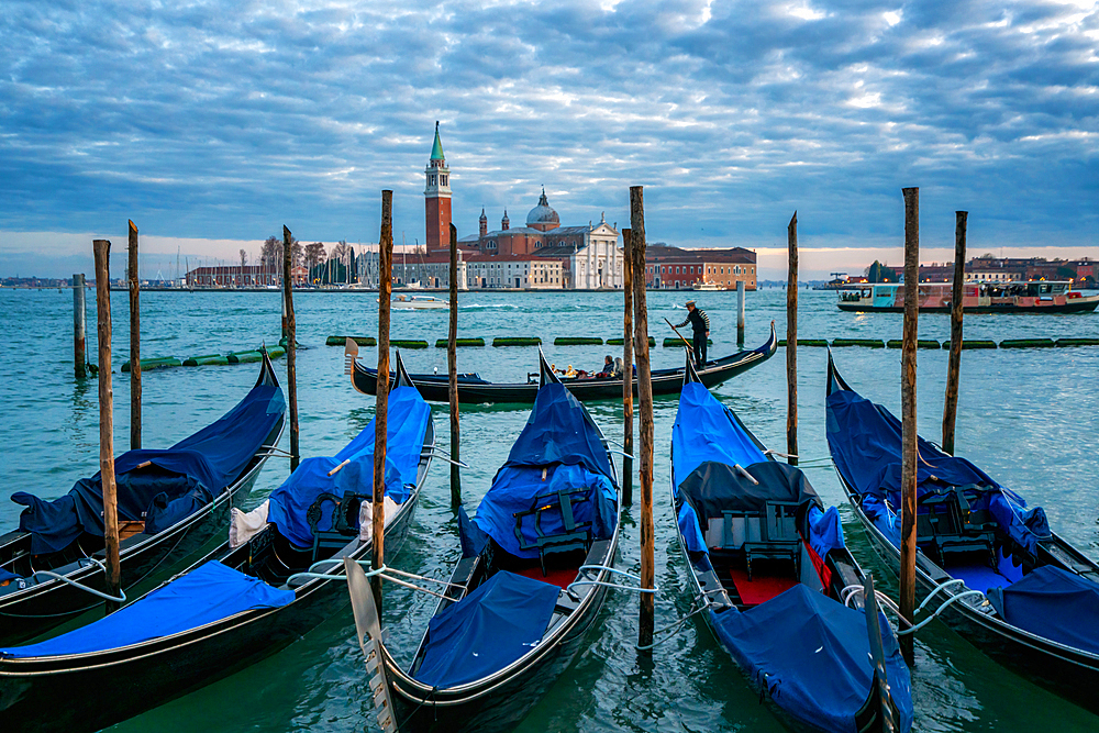 Gondolier paddling a gondola with San Giorgio Maggiore island and Basilica in the background at sunset, Venice, UNESCO World Heritage Site, Veneto, Italy, Europe