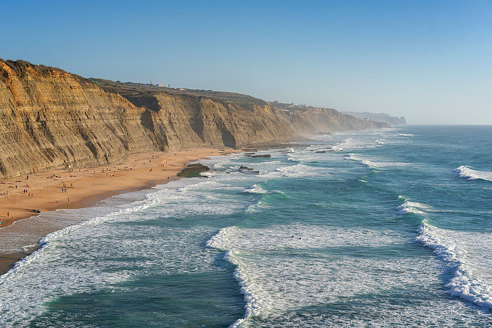 Magoito beach with surfers surfing on the sea waves, near Sintra, Portugal, Europe