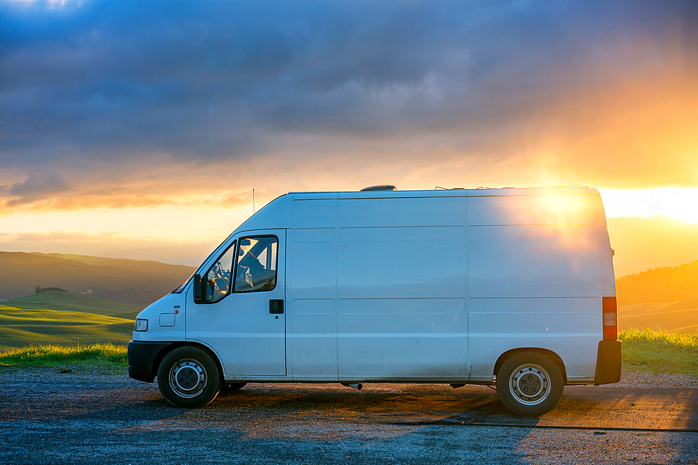 Camper van parked on the side of the road on a green Tuscan landscape at sunset, Tuscany, Italy, Europe