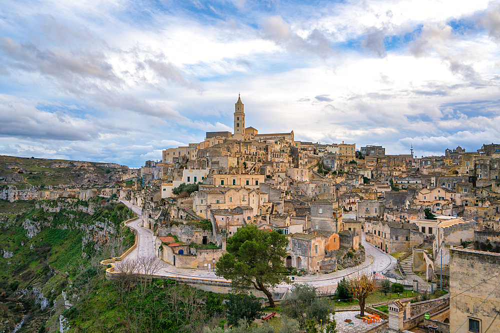 Matera ancient city with traditional stone houses with Maria Santissima della Bruna and Sant'Eustachio cathedral on the top, in Italy