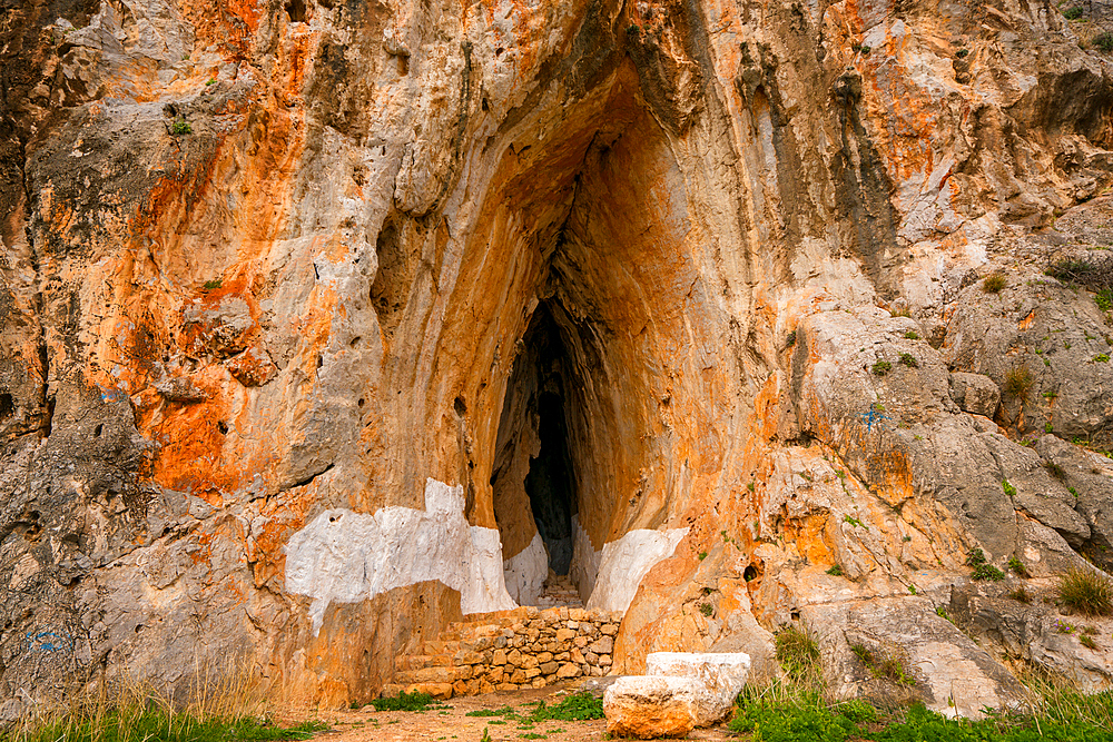 Cave of Elafonisos island with orange rock color painted in white, in Greece