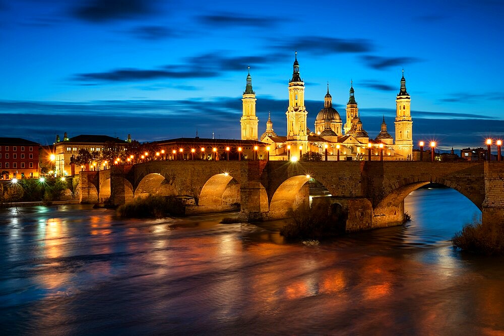 Basilica del Pilar Cathedral with stone bridge crossing Ebro River at night, Zaragoza, Aragon, Spain, Europe