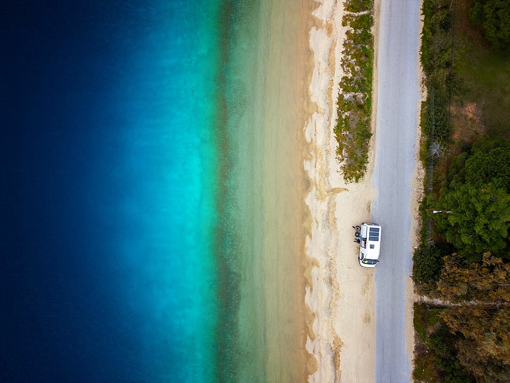 Camper van drone top aerial view parked on a wild beach in Porto Koufo, Greece