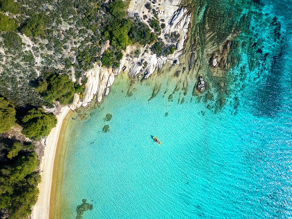 Diaporos island with wild beaches and a kayak on the turquoise water drone top aerial view in Greece