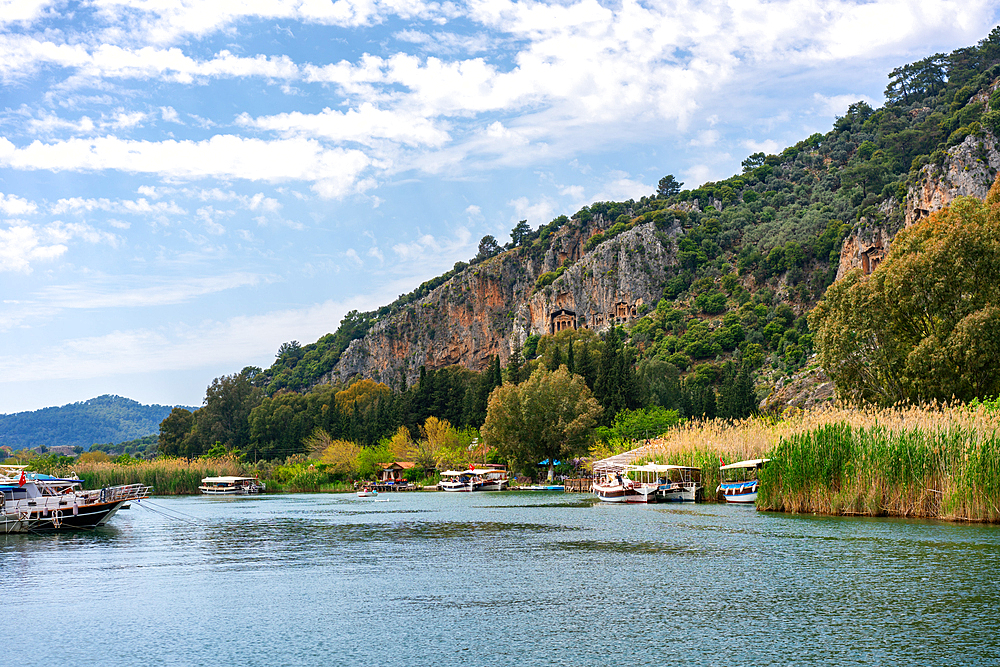 Tourist boats in Dalyan bay with Tombs of the kings carved on the hills in Turkey