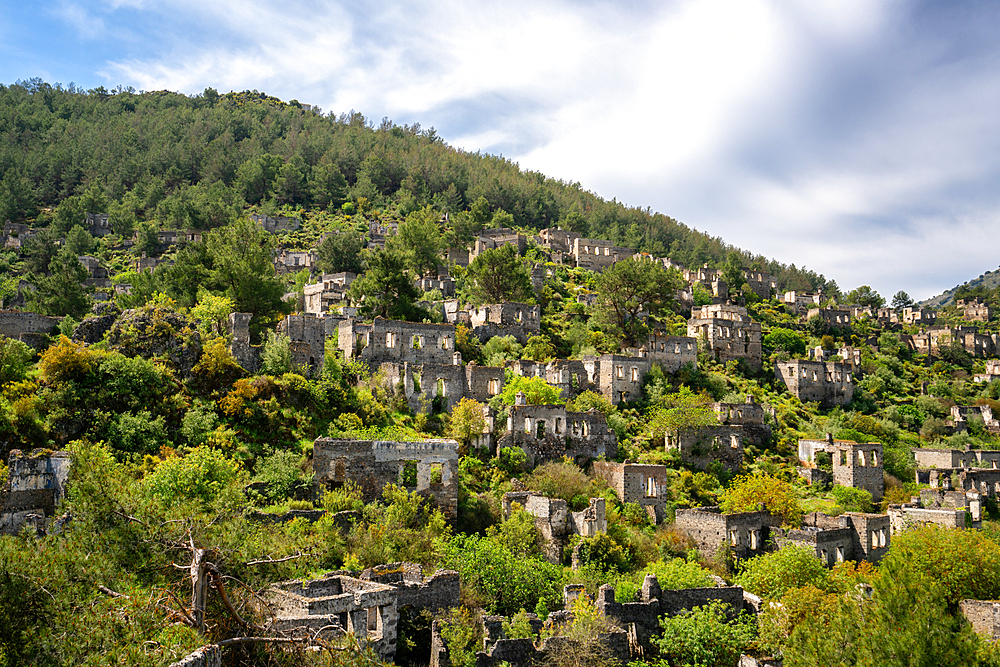 Kayakoy greek ghost town with abandoned houses in the mountains full of vegetations in Fethiye, Turkey