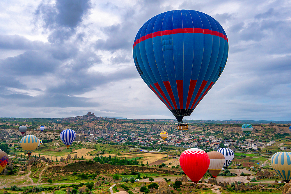 Hot air balloons in Cappadocia with Ortahisar city in the background at sunrise in Turkey