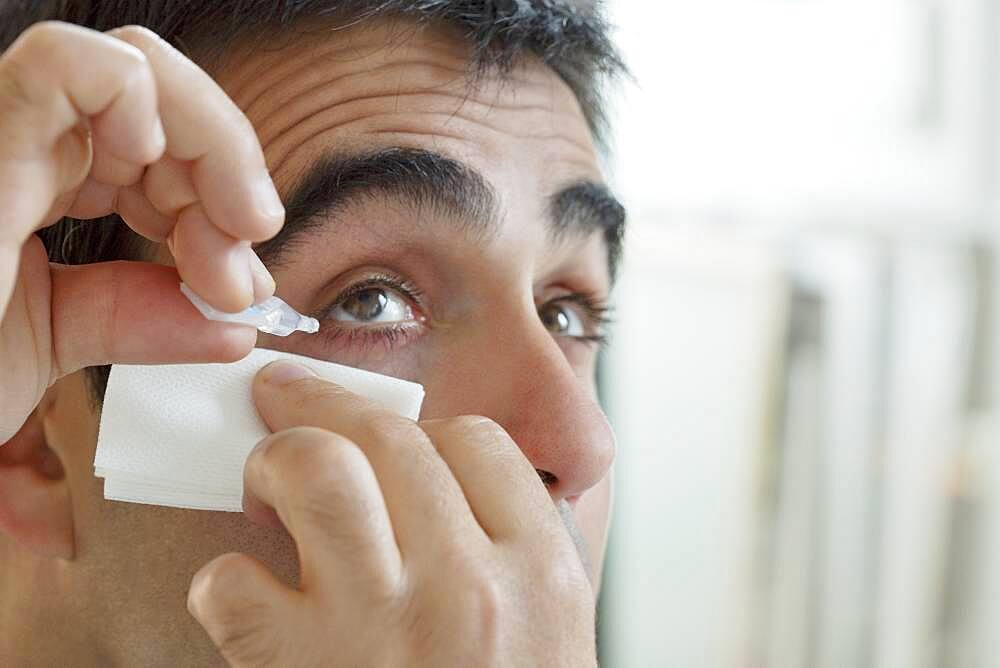 Man using eye lotion