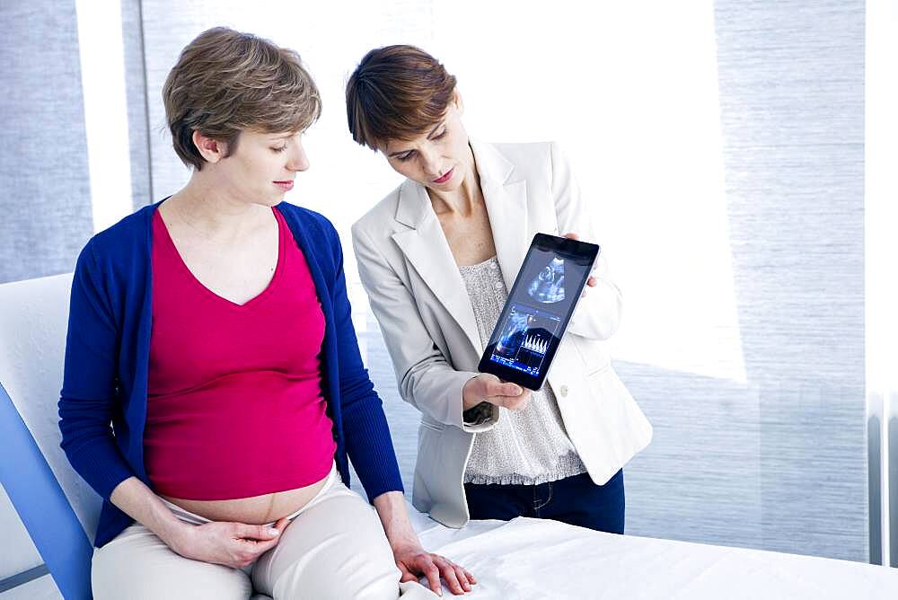 Doctor showing ultrasound scans to a pregnant woman.