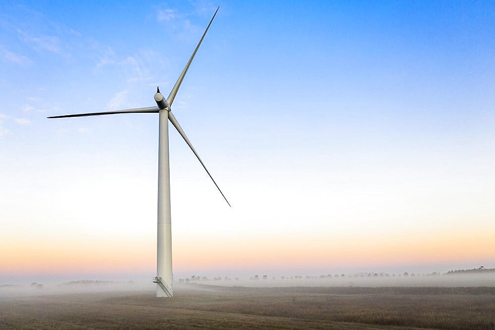 Commercial wind turbine in the early morning fog at sunrise in the English countryside