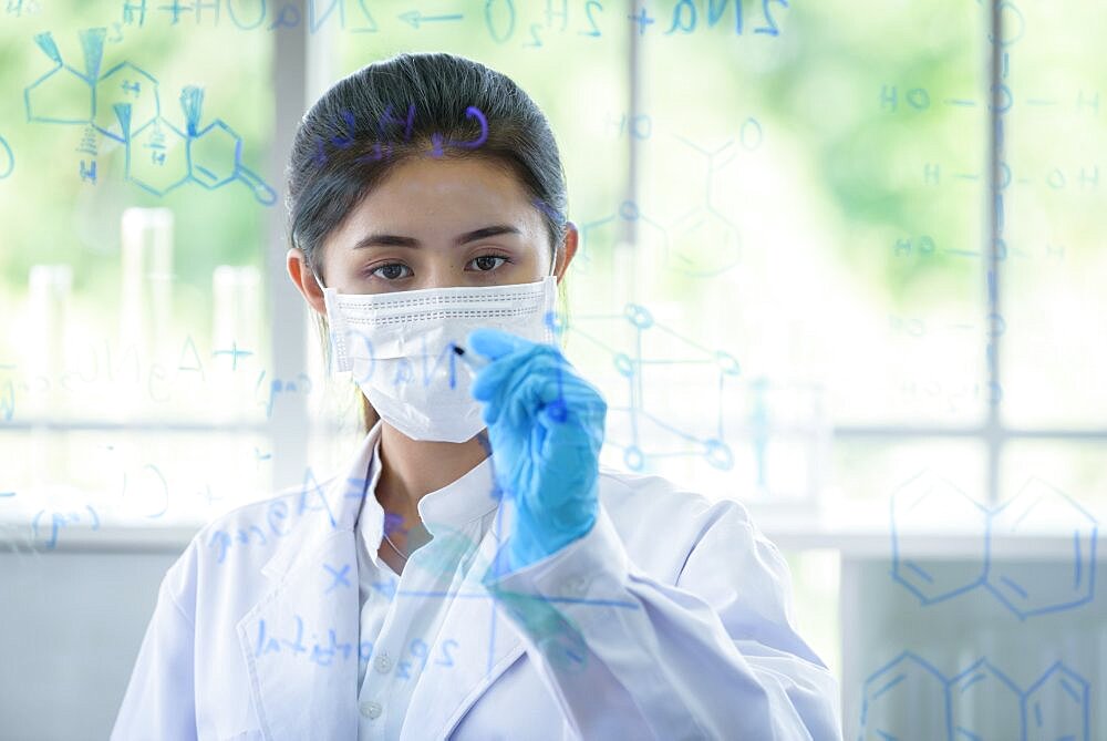 Asian young girl student scientist is writing and researching in laboratory.