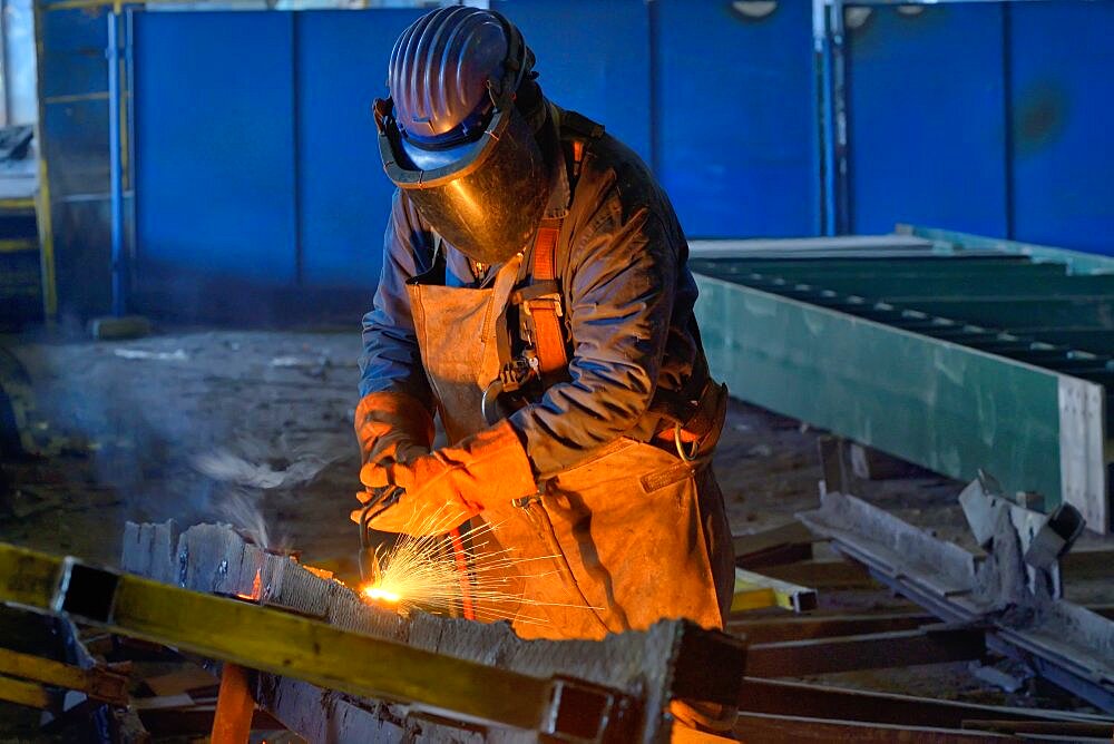 Welder welding metal in plant.