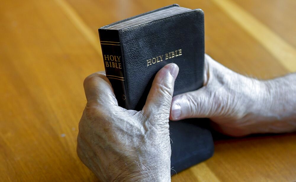 Holding the bible over table.