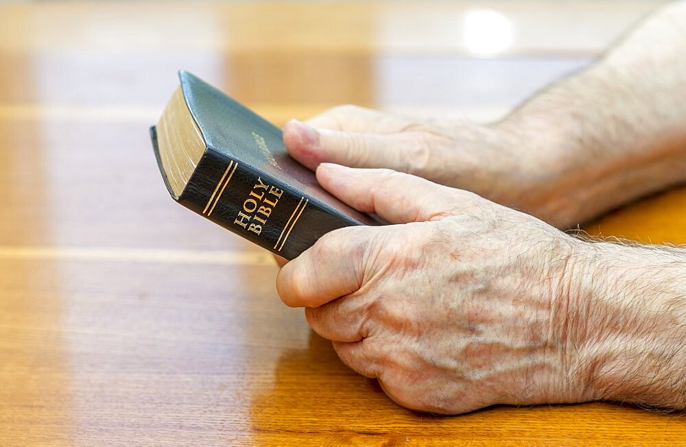 Holding the bible over table.