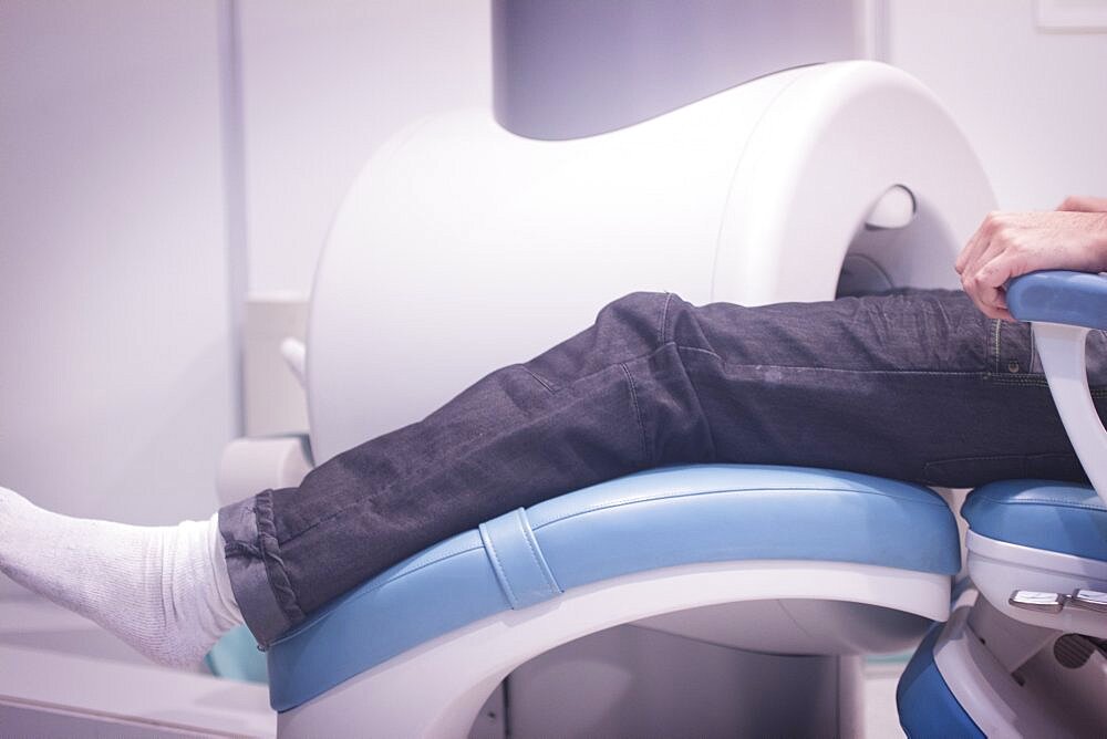 Patient and Doctor in fully open high field Magnetic Resonance Image MRI CAT Scan scanning knee and leg.