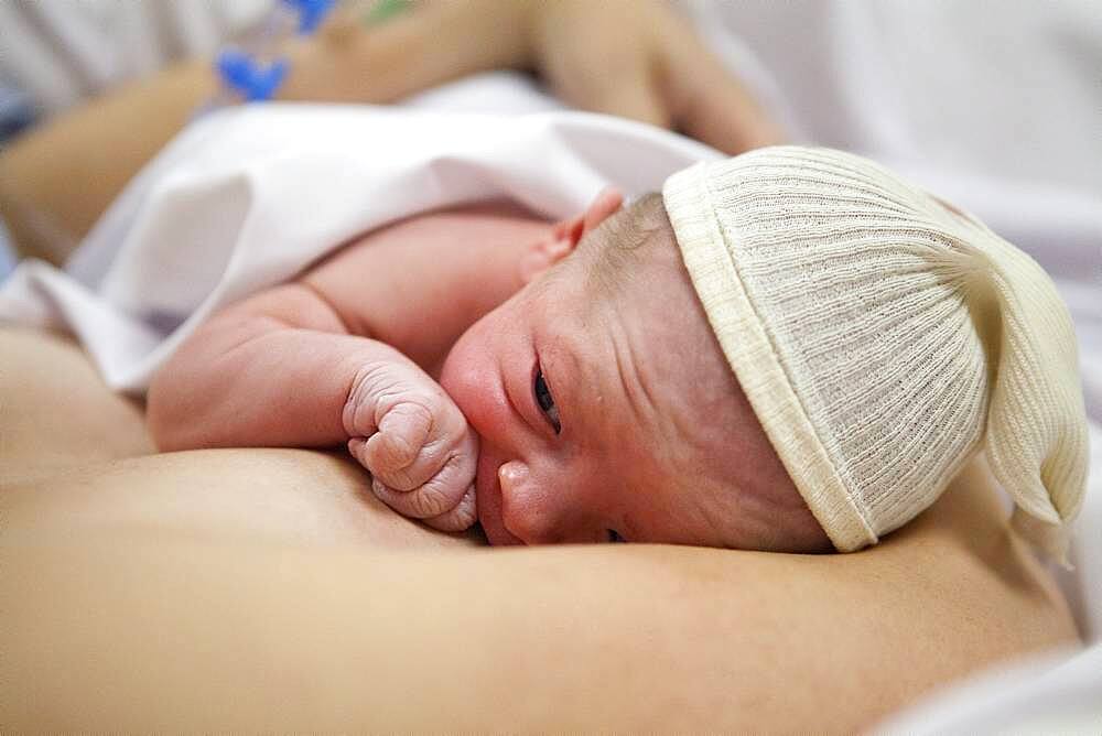 In the delivery room, skin to skin contact and first attempt at breast-feeding.