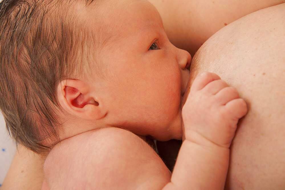 Mother breast feeding 2-week-old baby.