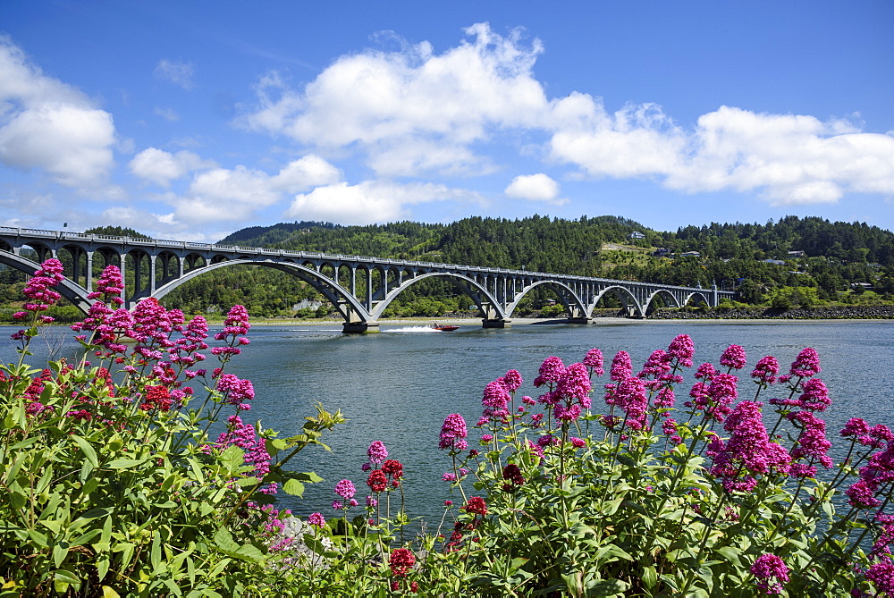 Isaac Lee Patterson Bridge on the Rogue River, with a jet boat passing under; from Jot's Resort in Gold Beach on the southern Oregon coast.