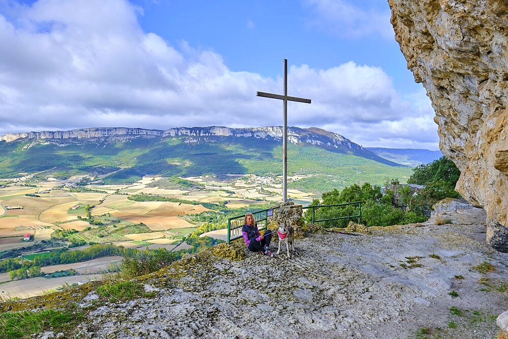 Young mature hiker woman with a dog in a viewpoint. Lazkua viewpoint and Loquiz Sierra at background.
Tierra Estella county, Navarre, Spain, Europe.