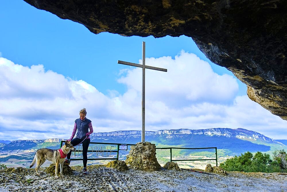 Young mature hiker woman with a dog in a viewpoint. Lazkua viewpoint and Loquiz Sierra at background.
Tierra Estella county, Navarre, Spain, Europe.