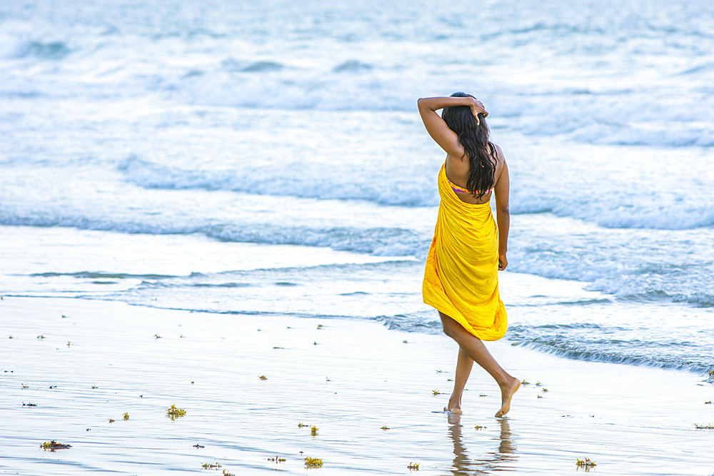 Woman walking on beach at Magdalena Grand Beach Resort on the island of Tobago; Trinidad and Tobago.