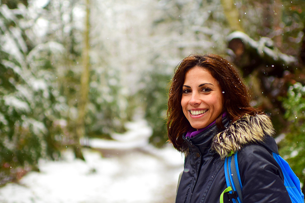 Smiling young attractive caucasian female hiker in the snowy mountains of the Pyrenees during winter season, Aragon, Spain