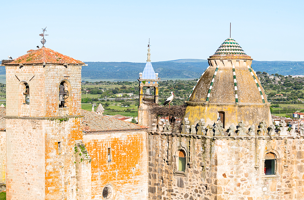 Nesting storks on the the Iglesia de San Martin, on the left and centre, and Torre del Alfiler, on the right, Trujillo, Caceres, Extremadura, Spain, Europe