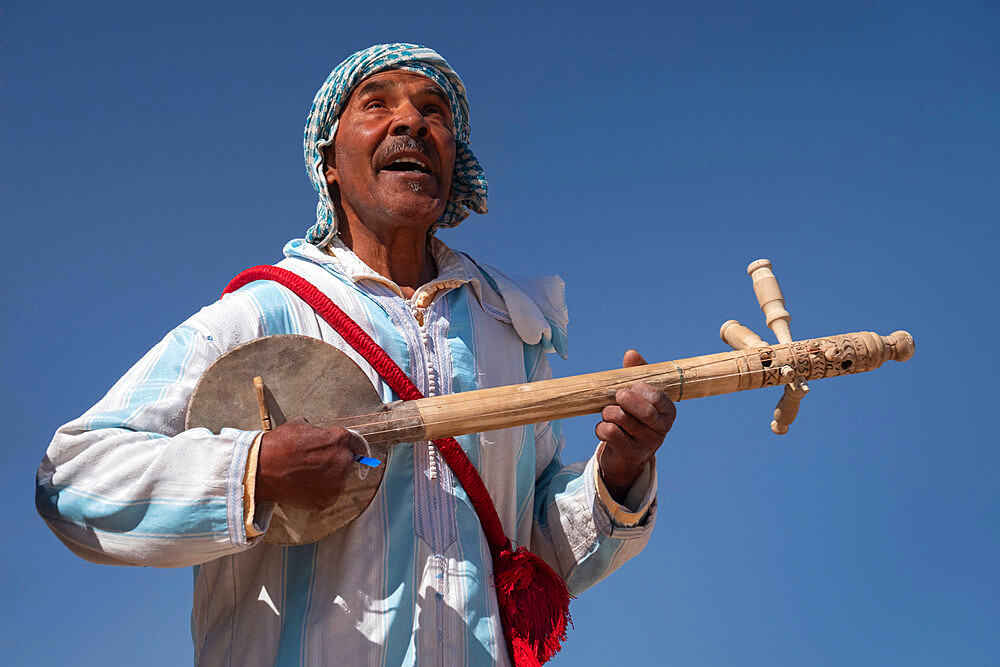 Moroccan man in traditional dress playing a traditional Gimbri instrument, Ouarzazate, Atlas Mountains, Morocco, North Africa, Africa