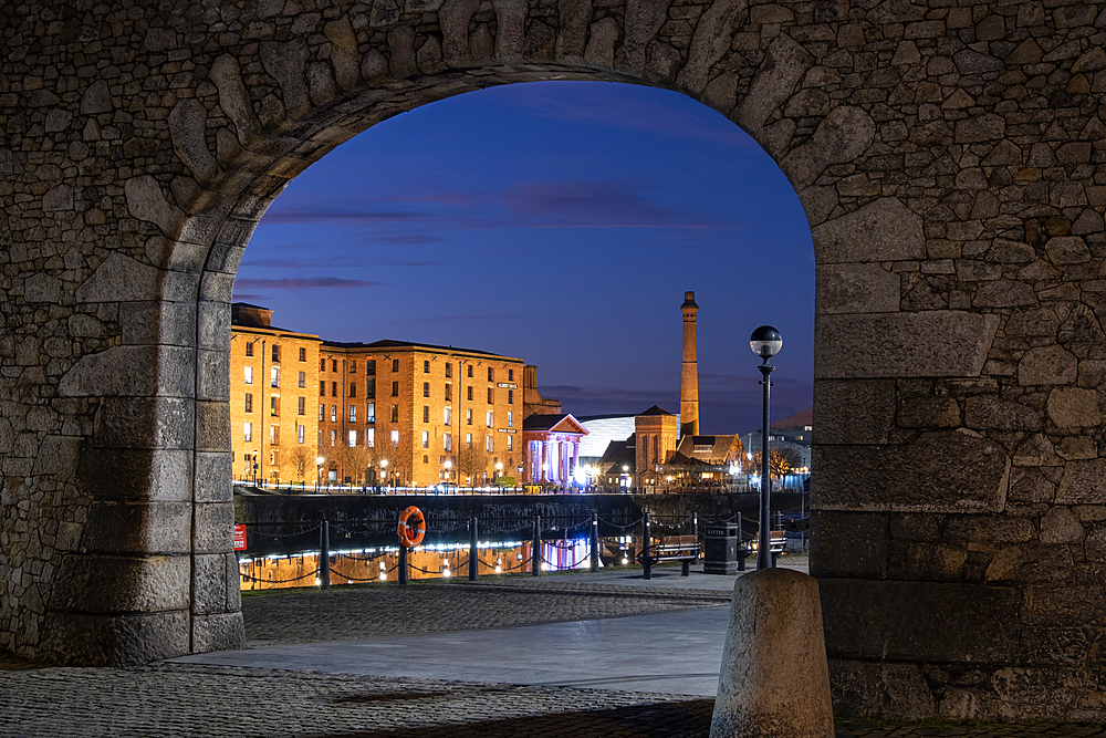 The Albert Dock and Pumphouse viewed through a remnant of the original dock wall at night, Liverpool Waterfront, Liverpool, Merseyside, England, United Kingdom, Europe