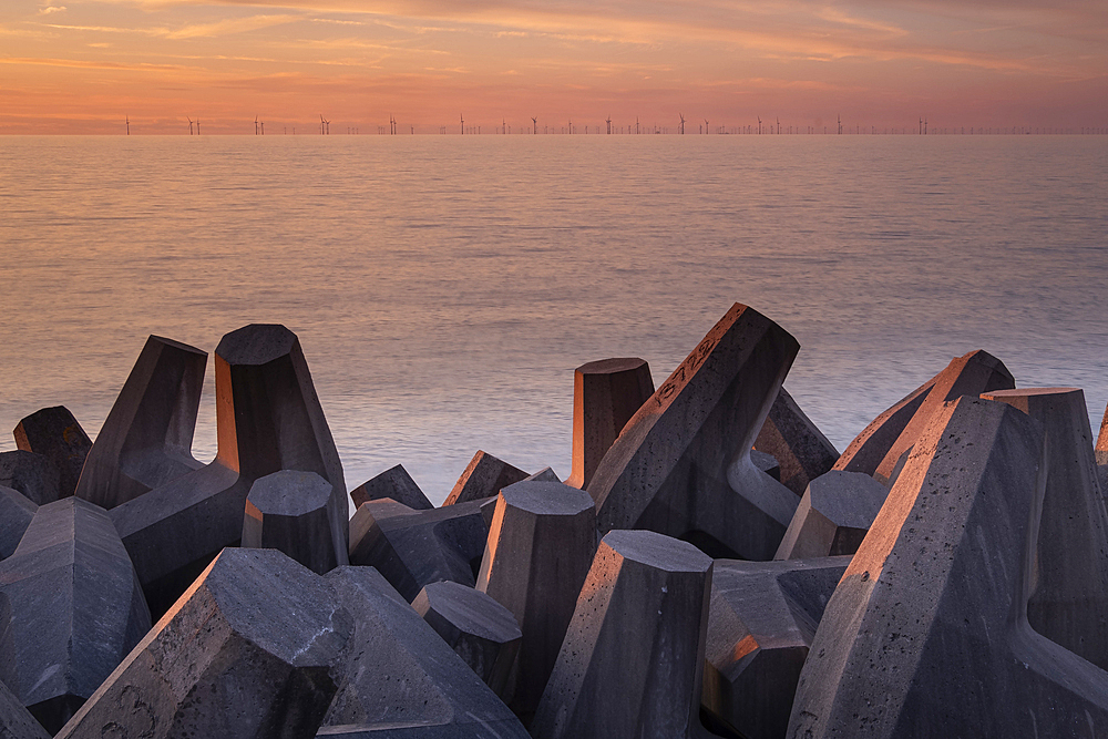 Concrete Sea Defences on Llanddulas Beach backed by the distant Gwynt y Mor Offshore Wind Farm at sunset, Llanddulas, near Abergele, Conwy County Borough, North Wales, UK