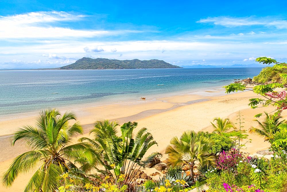 Boat on the beach seen through lush vegetation at Nosy Komba island, in the North West of Madagascar.