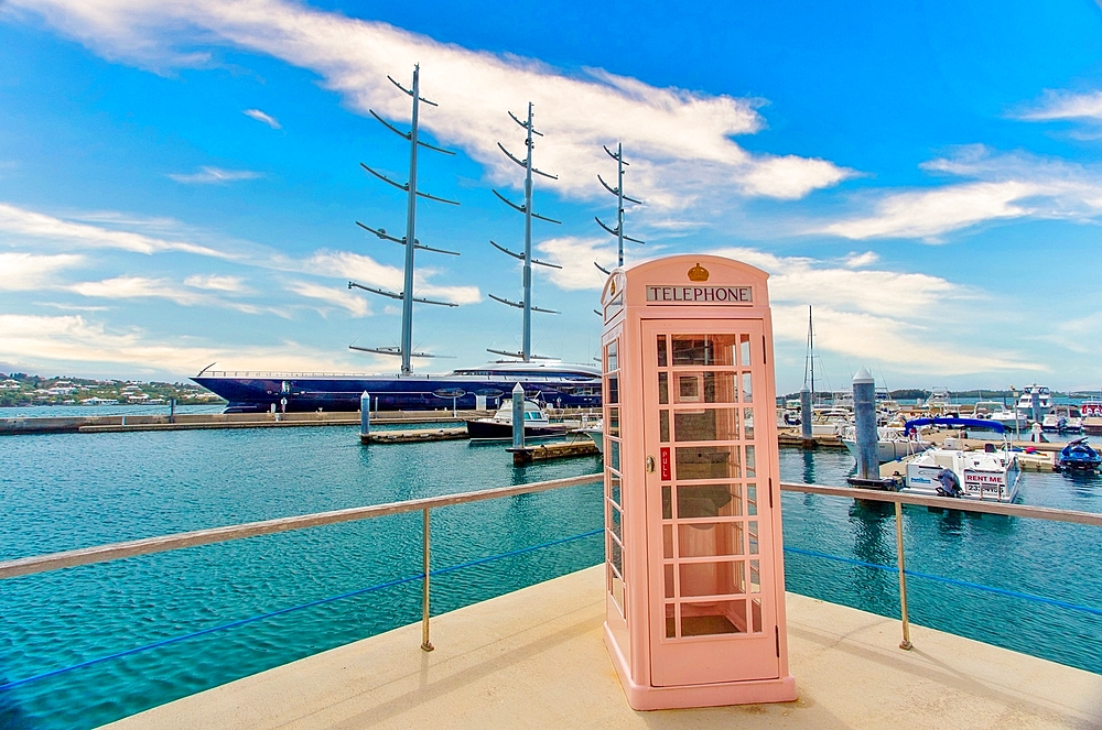 An old British telephone kiosk, with a three masted sailing ship moored behind, Hamilton, Bermuda, North Atlantic, North America