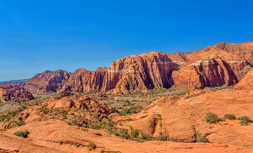 The Red Mountains rising behind the petrified sand dunes at Snow Canyon State Park, Southern Utah, USA. Many famous films were made in the park which forms part of the Red Cliffs Desert Reserve.