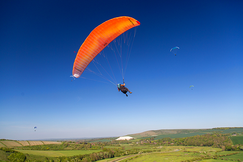Paragliders soaring above the picturesque Cuckmere Valley and South Downs at High and Over, near Alfriston, East Sussex, UK